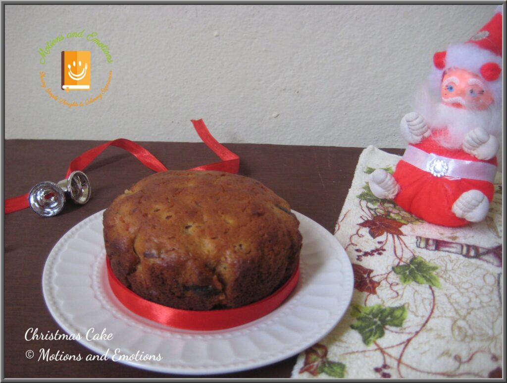 Christmas cake on a white plate along with Christmas decorations