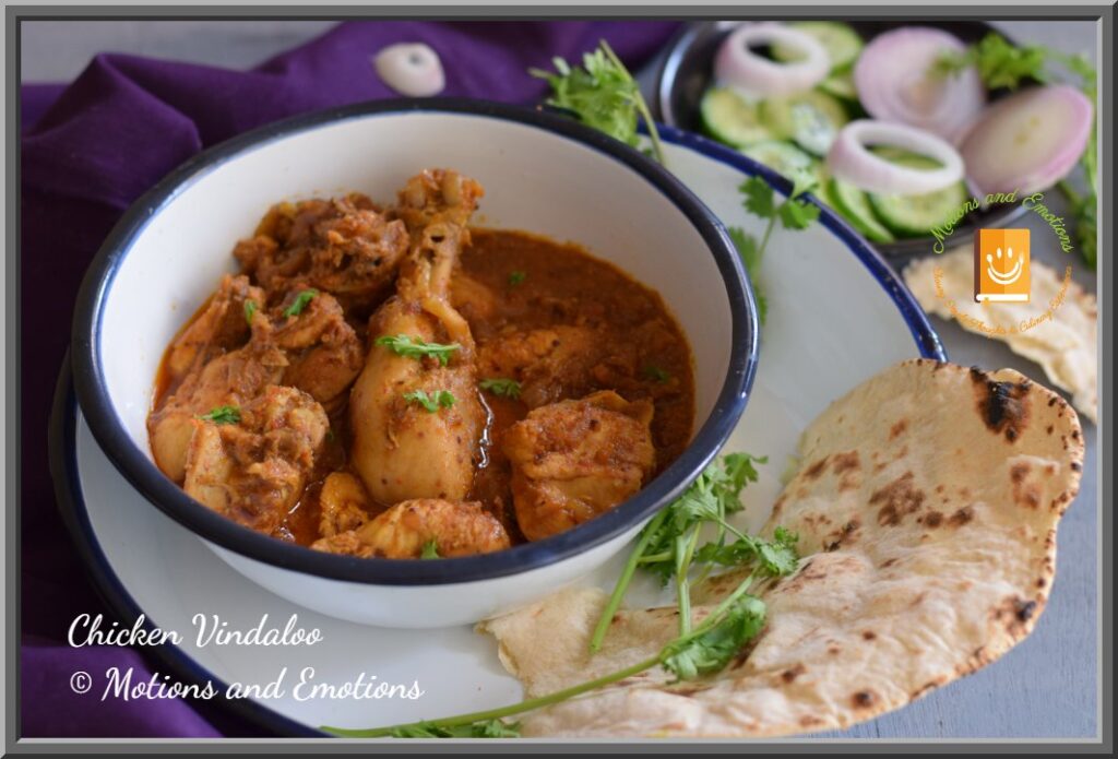 Goan Chicken vindaloo served in a white bowl along with naan and salad