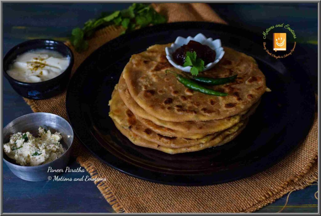 Stacked paneer paratha served on a black plate