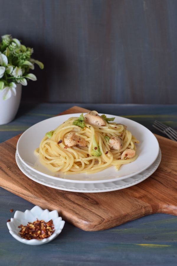 Spaghetti Aglio olio served on a white half plate kept of wooden board