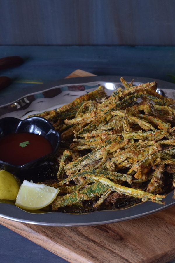 crispy okra served in a plate with ketchup and lemon