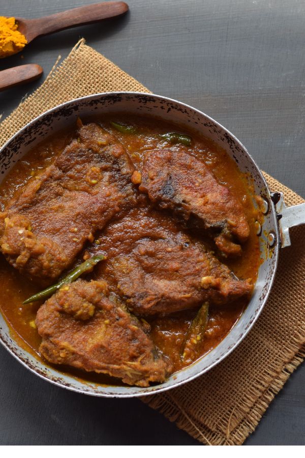 macher kalia served in an aluminum pan along with spices