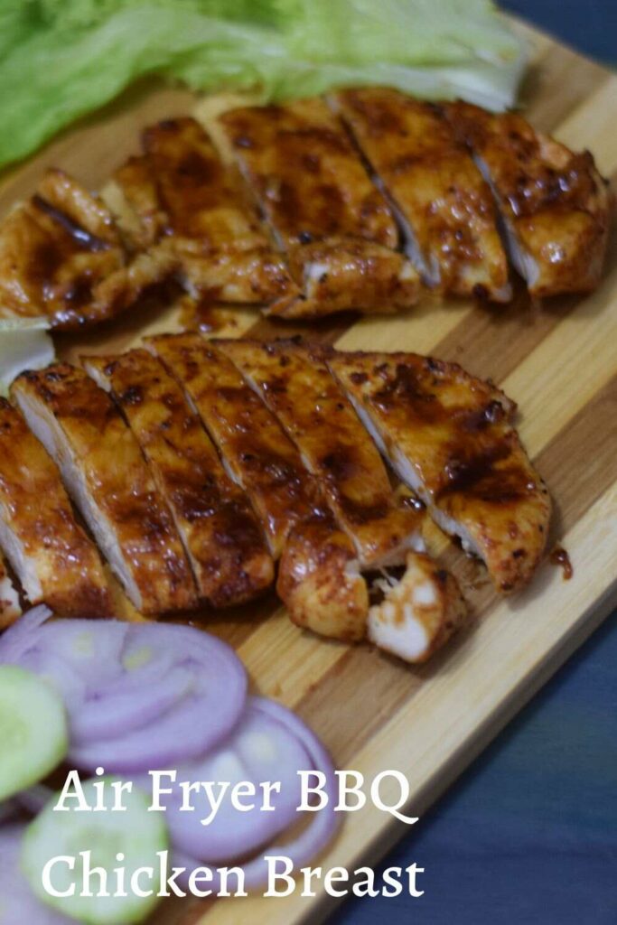 sliced bbq chicken breasts on wooden board with salads