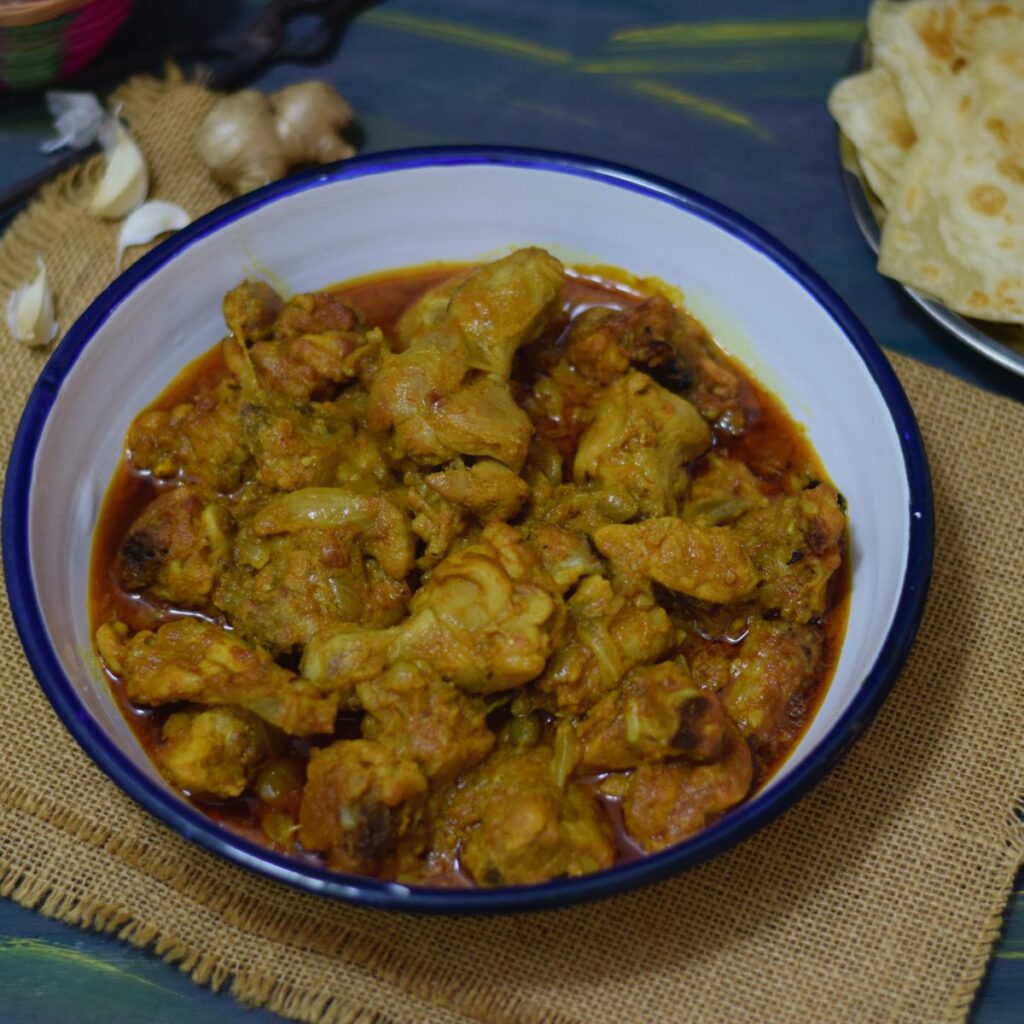 Chicken kosha in a white enamel plate along with paratha