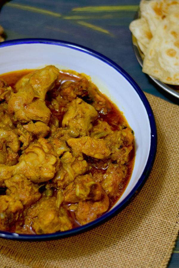 A plate full of chicken kosha along with paratha