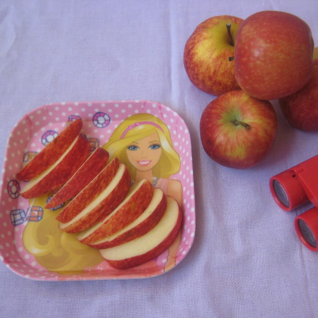 sliced apple in a plate, along with apple in the background