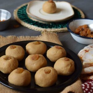 nolen gurer sondesh served on a black plate along with a sondesh served in a saucer and jaggery in the background