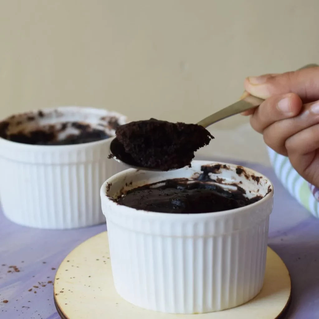 mug cake in ramekins and a hand holding a spoon with cake