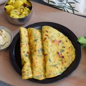 methi thepla on black plate along with aloo and curd