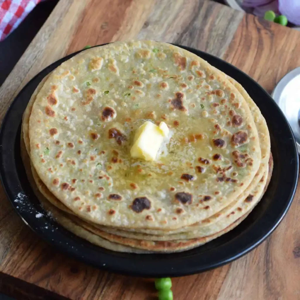 stack of paratha on a black plate and a dollop of butter on top
