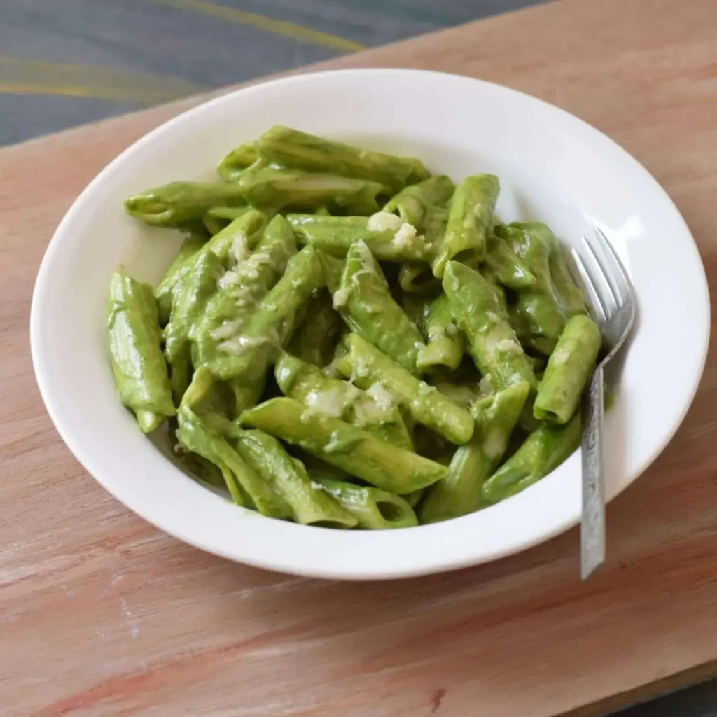 green sauce pasta in a white bowl with fork