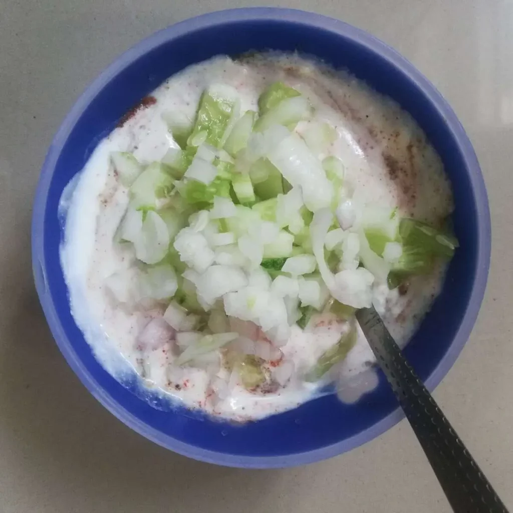 yogurt along with spices, chopped cucumber and onion