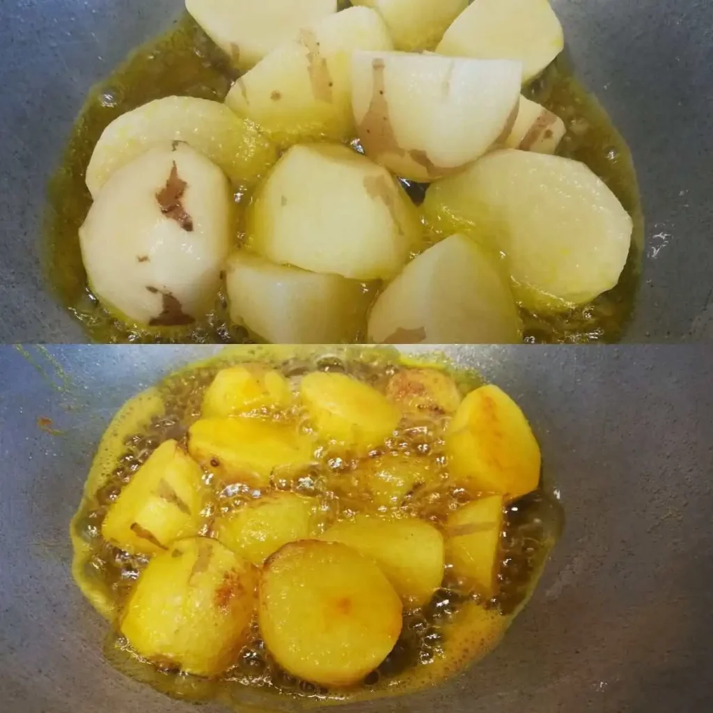 Potatoes are getting fried in oil with turmeric powder and salt