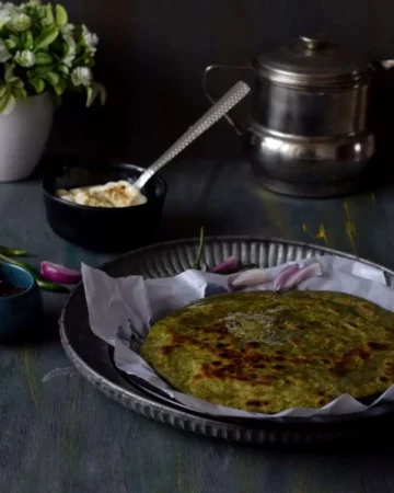 palak paneer paratha in a plate along with pickle and curd