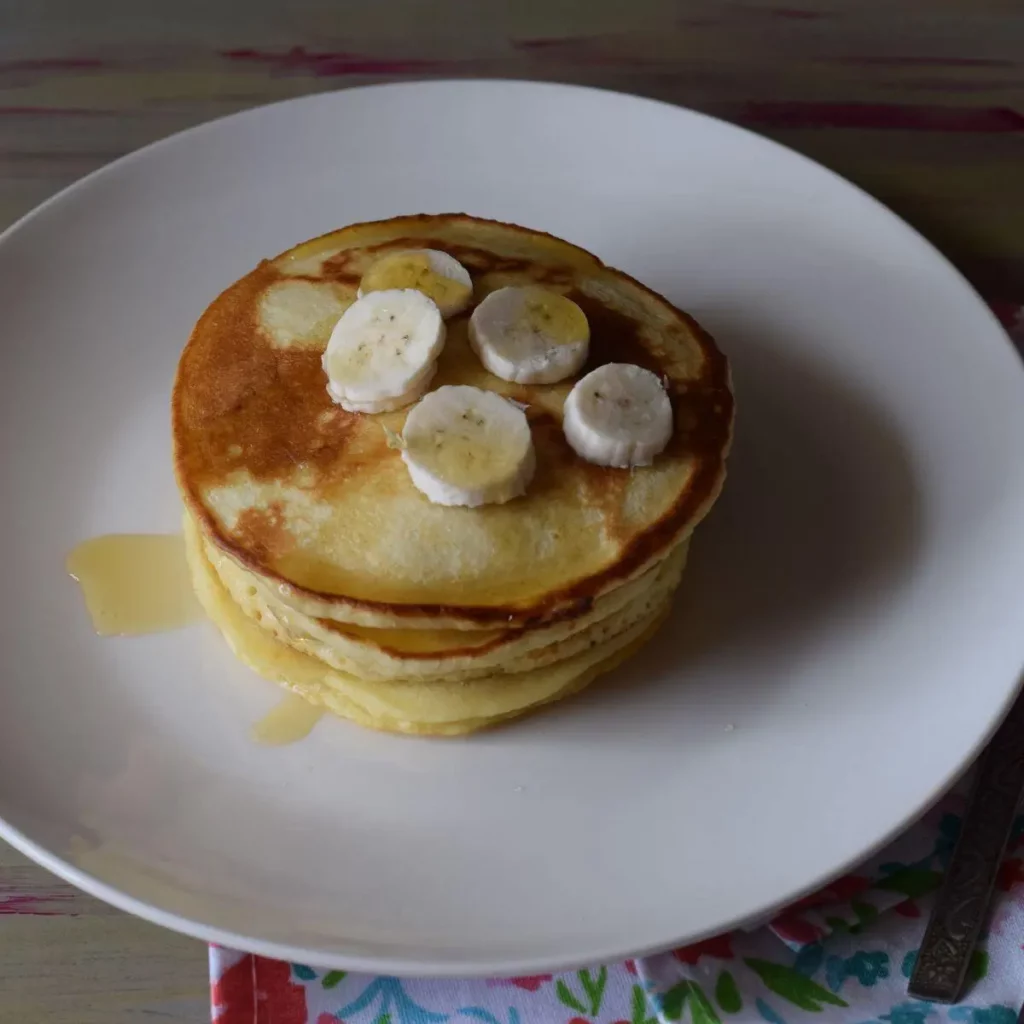 stack of pancakes topped with banana slices topview