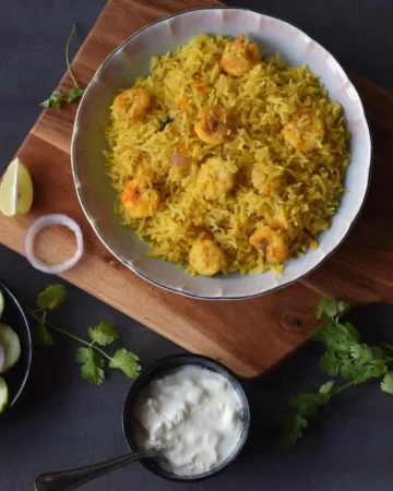 bowlful of prawn pulao along with curd and salad