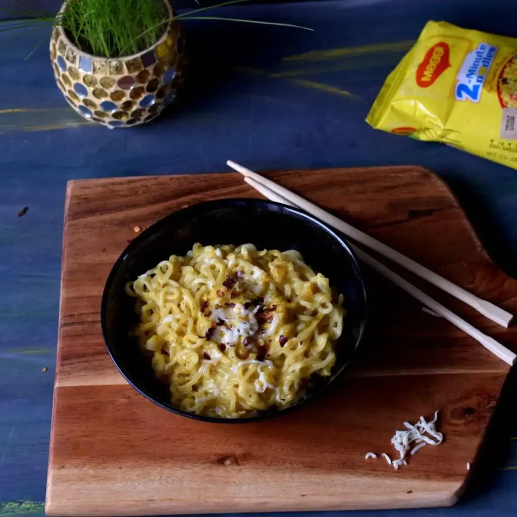 cheese Maggi in a black bowl with chopsticks