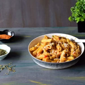 tandoori pasta in a pasta plate along with kasuri methi and tandoori masala in the background