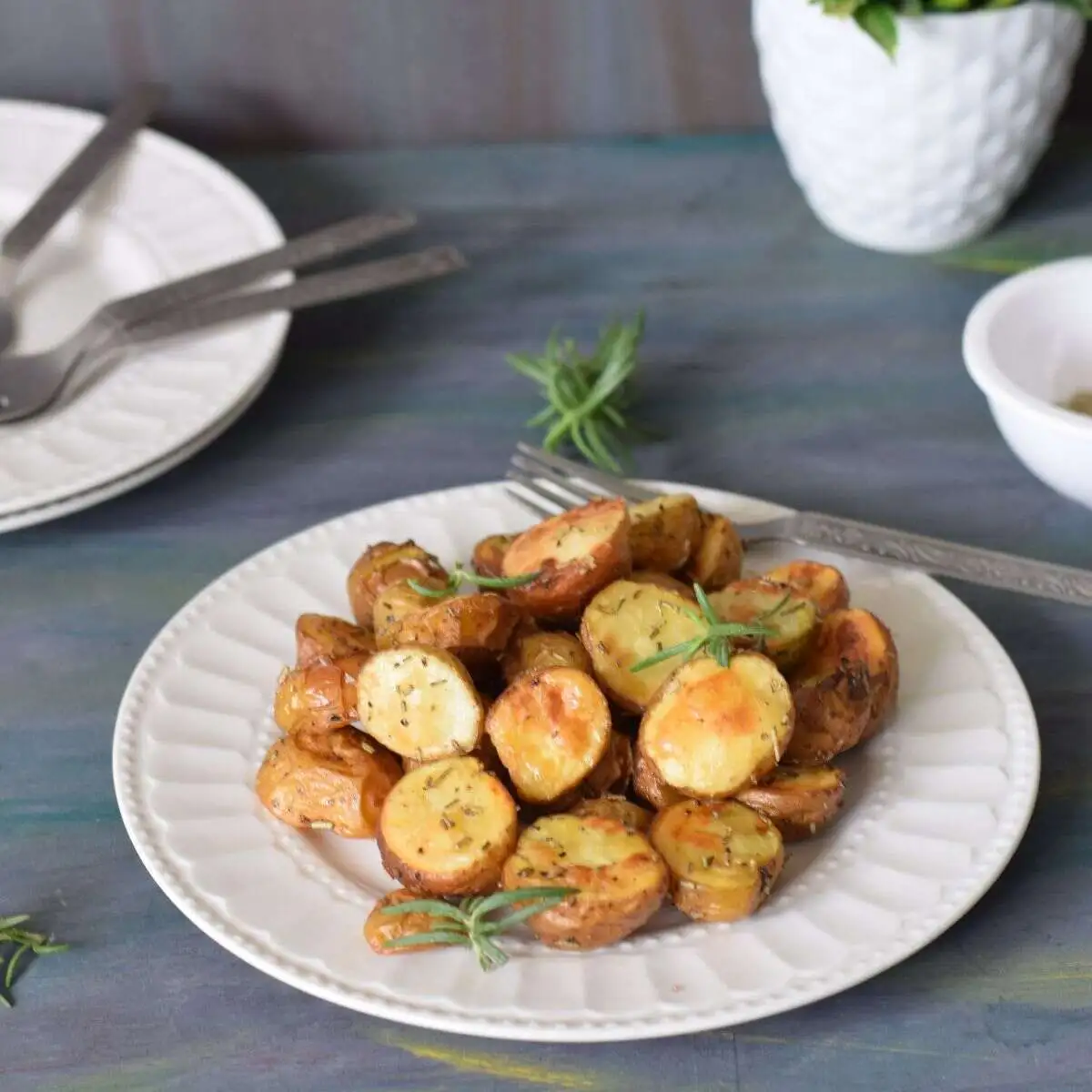 crispy roasted baby potatoes with rosemary served on a white plate along with fork