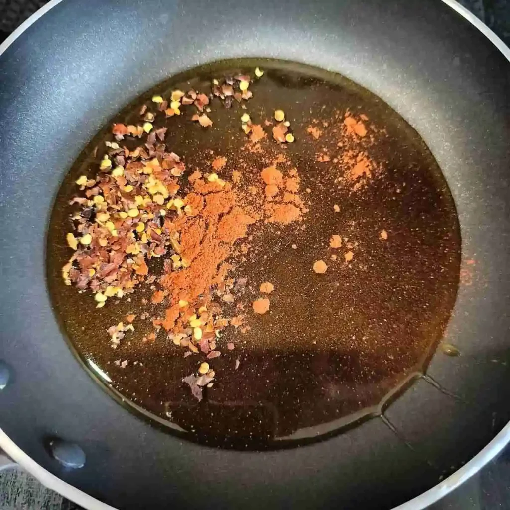 honey along with chili flakes and cayenne powder in a pan