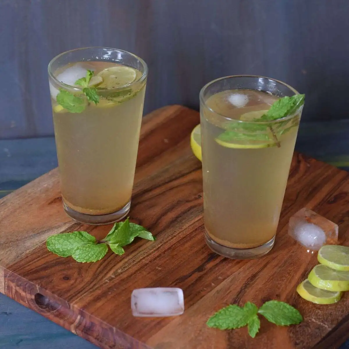 Masala Shikanji served in two glasses along with ice cubes, mint and lemon