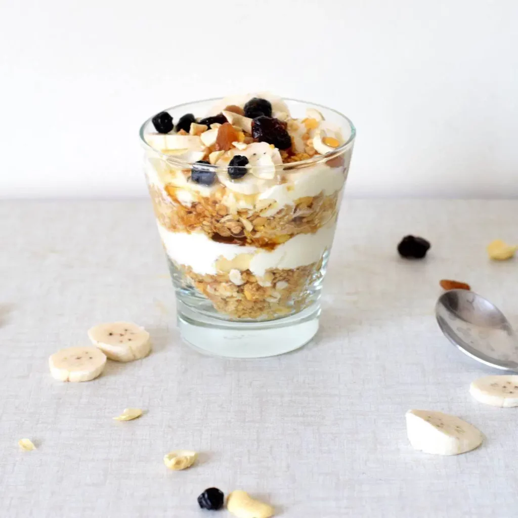 banana yogurt parfait in a glass and banana slices in the background