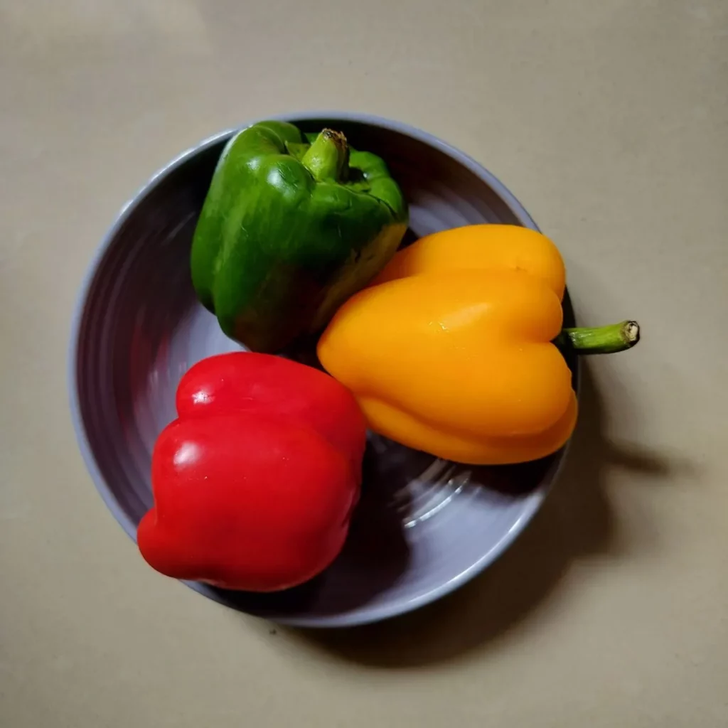 green, red and yellow bell pepper in a bowl
