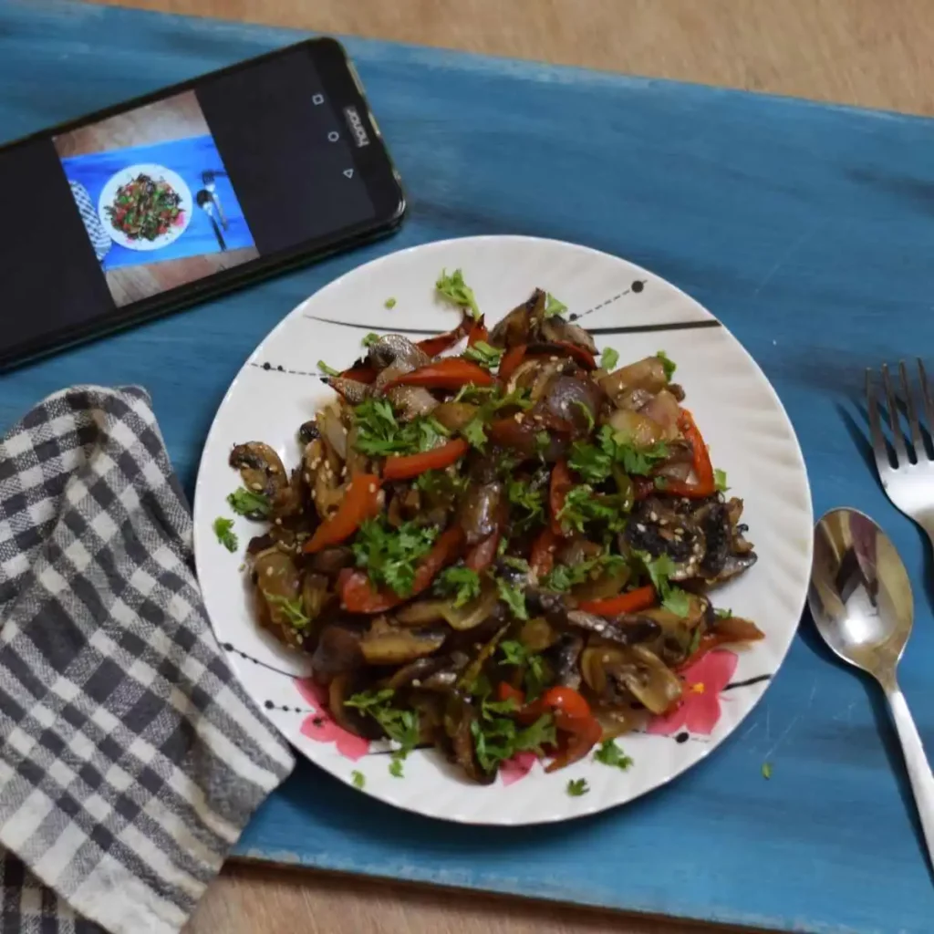 mushroom stir fry in a white plate along with mobile