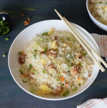 Chicken fried rice in a white bowl with chopsticks