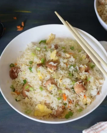 Chicken fried rice in a white bowl with chopsticks