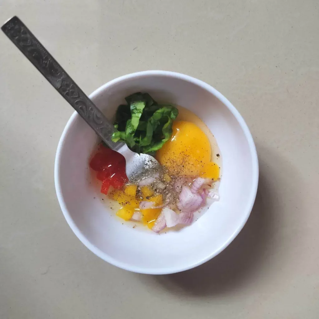 egg along with chopped vegetables in a bowl with fork