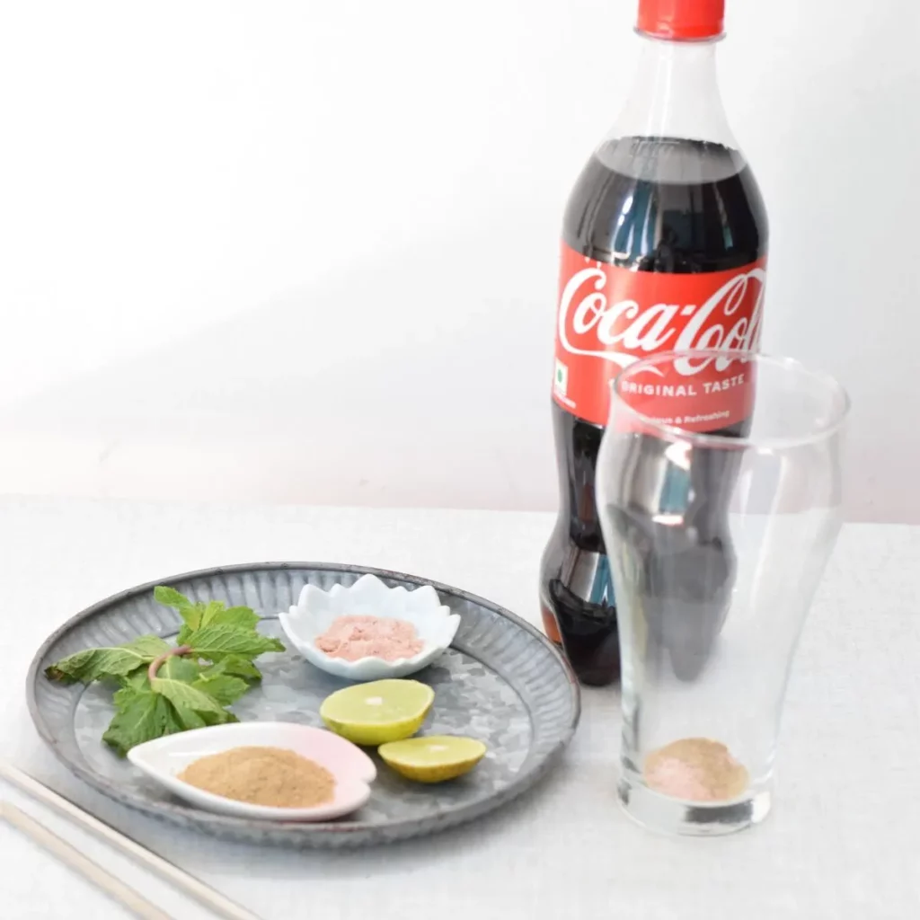 Coke bottle, glass, mint leaves, lemon and spices