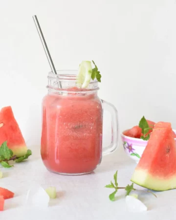 juice in a mason jar along with piece of watermelon and mint scattered