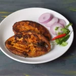 two king fish masala fry in a white plate along with salad