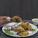 chicken kalmi kabab on plate and one kabab holding in hand